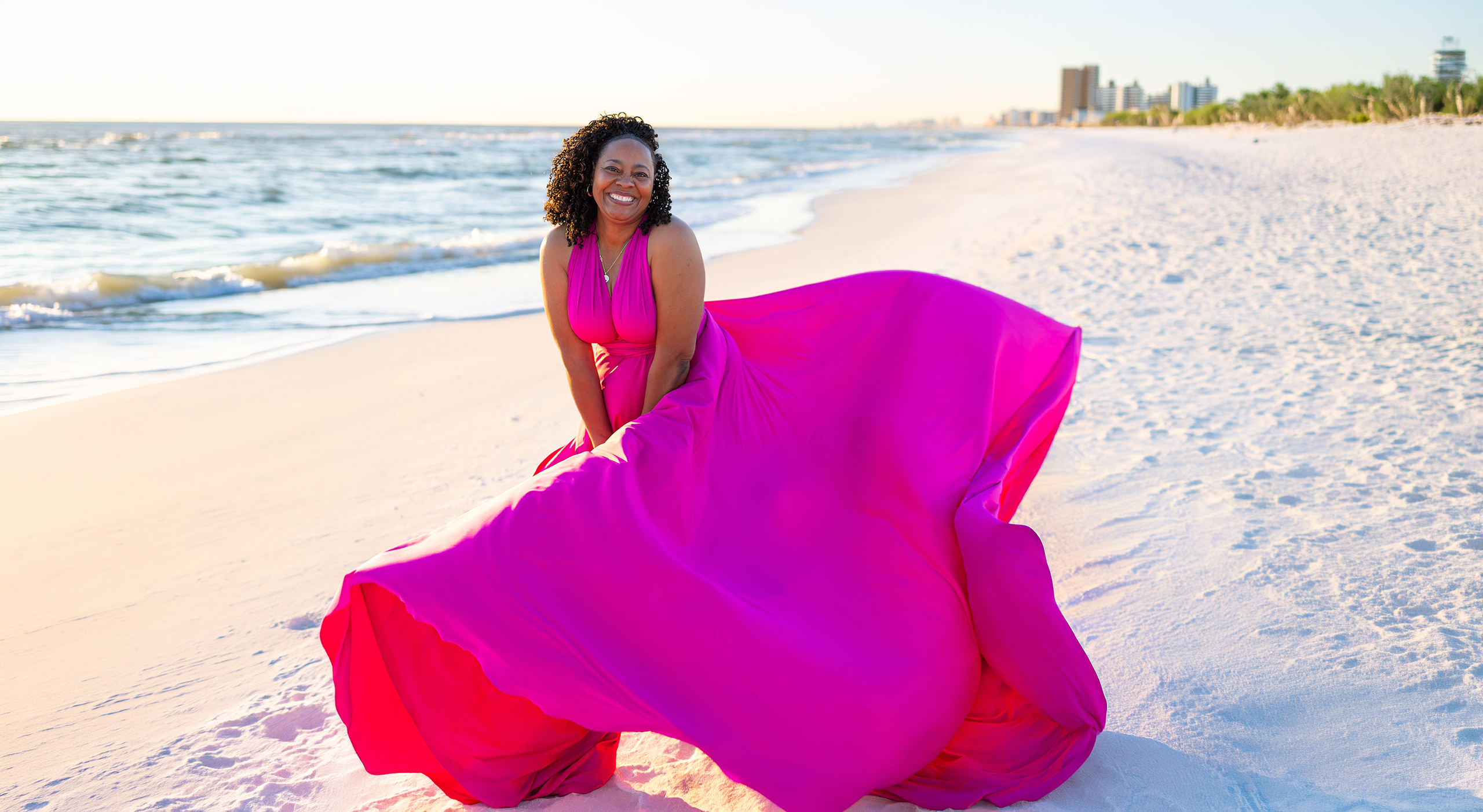 PANAMA~1 Woman in a magenta flying dress sitting on a white-sand beach