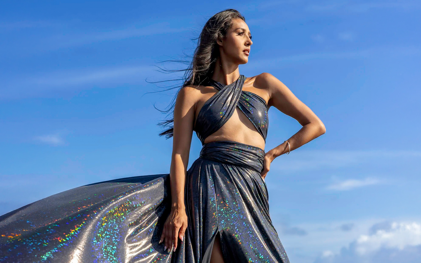 Woman in a black sequin flying dress against a bright blue sky