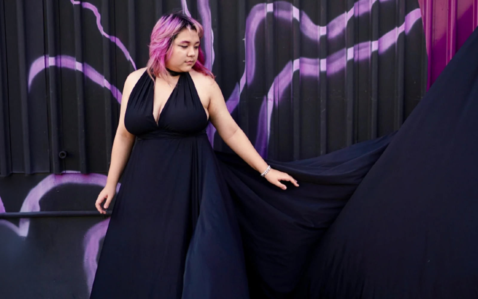 Woman in a black flying dress in a studio with a purple backdrop