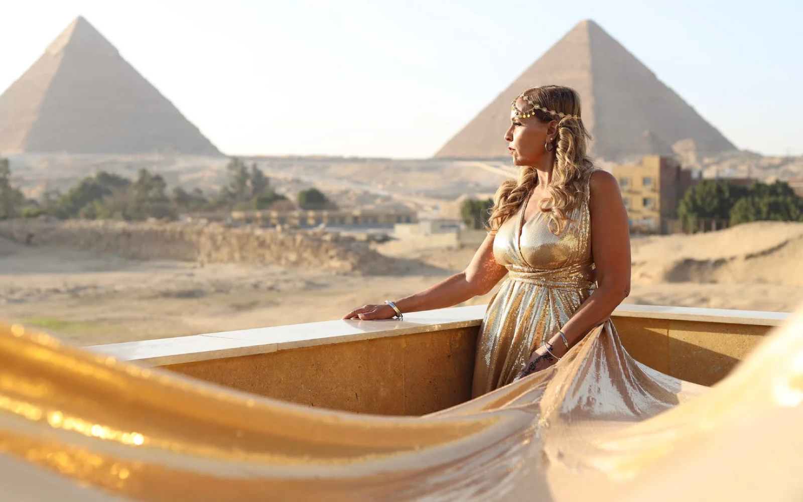 Woman in a gold sequin flying dress in front of the pyramids of Giza