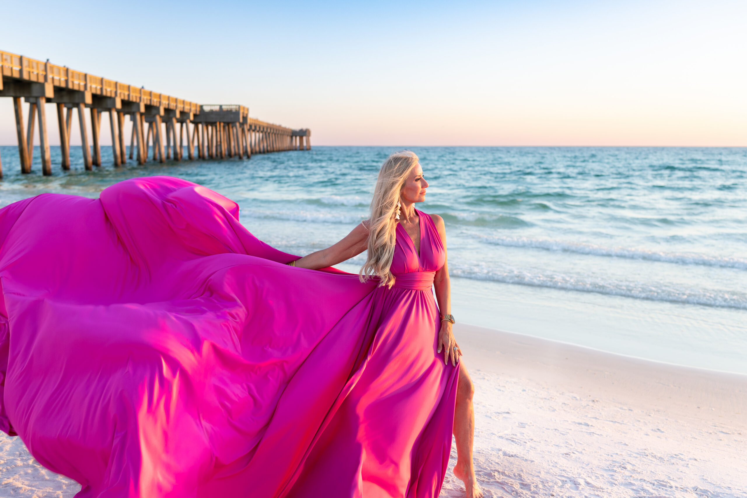 IMG_6400 Woman in a magenta flying dress on the beach near a pier